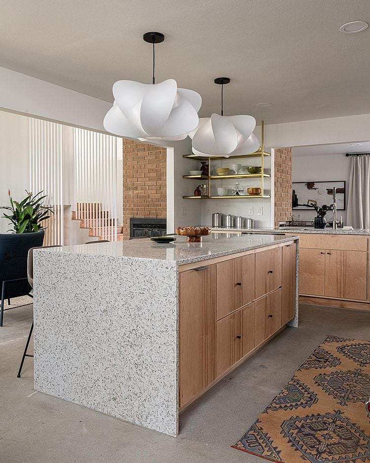 Unique terrazzo recycled glass countertops with waterfall edges make the kitchen island the focal point of this open concept space